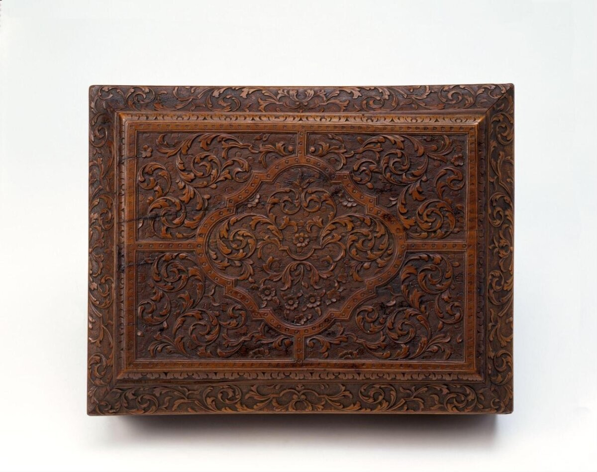 Box of carved cherry wood (bois de Sainte Lucie), the lid hinged and with concave sides, the whole visible surface covered with intricate arabesque motifs.