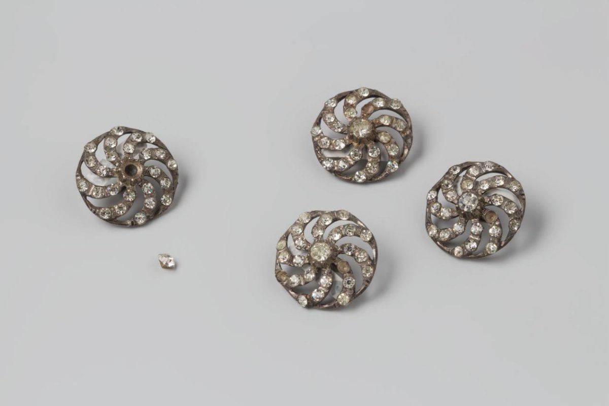 Button with a large stone in the centre around which are eight small ones on curved spokes