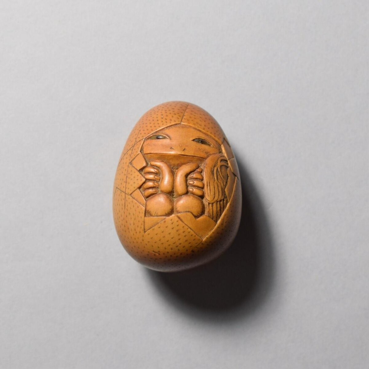Netsuke of a tengu hatching from an egg, carved and stained wood, signed Shumin