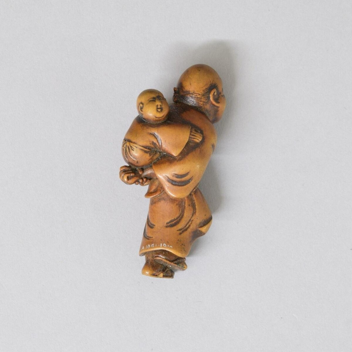 Netsuke, boxwood carved with an old man with a child on his back, Japan, about 1800.