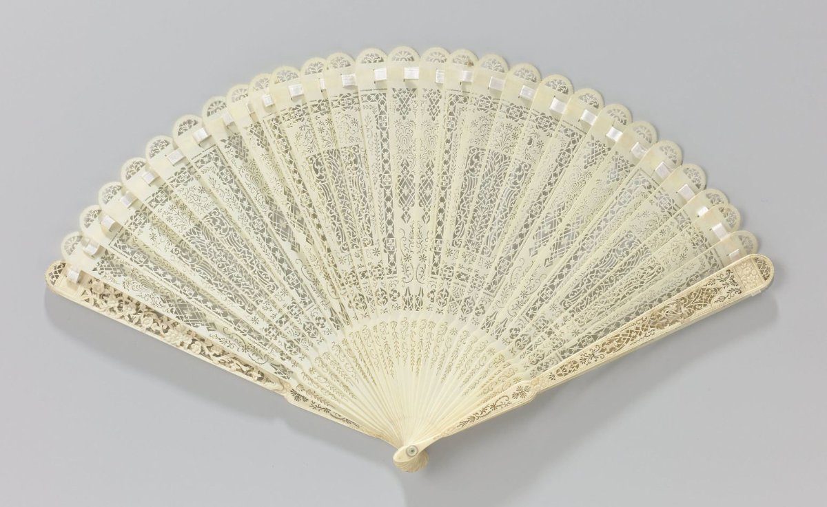Brisé fan of carved ivory with a symmetrically structured pattern and on the guards a marriage altar below two birds near a trophy