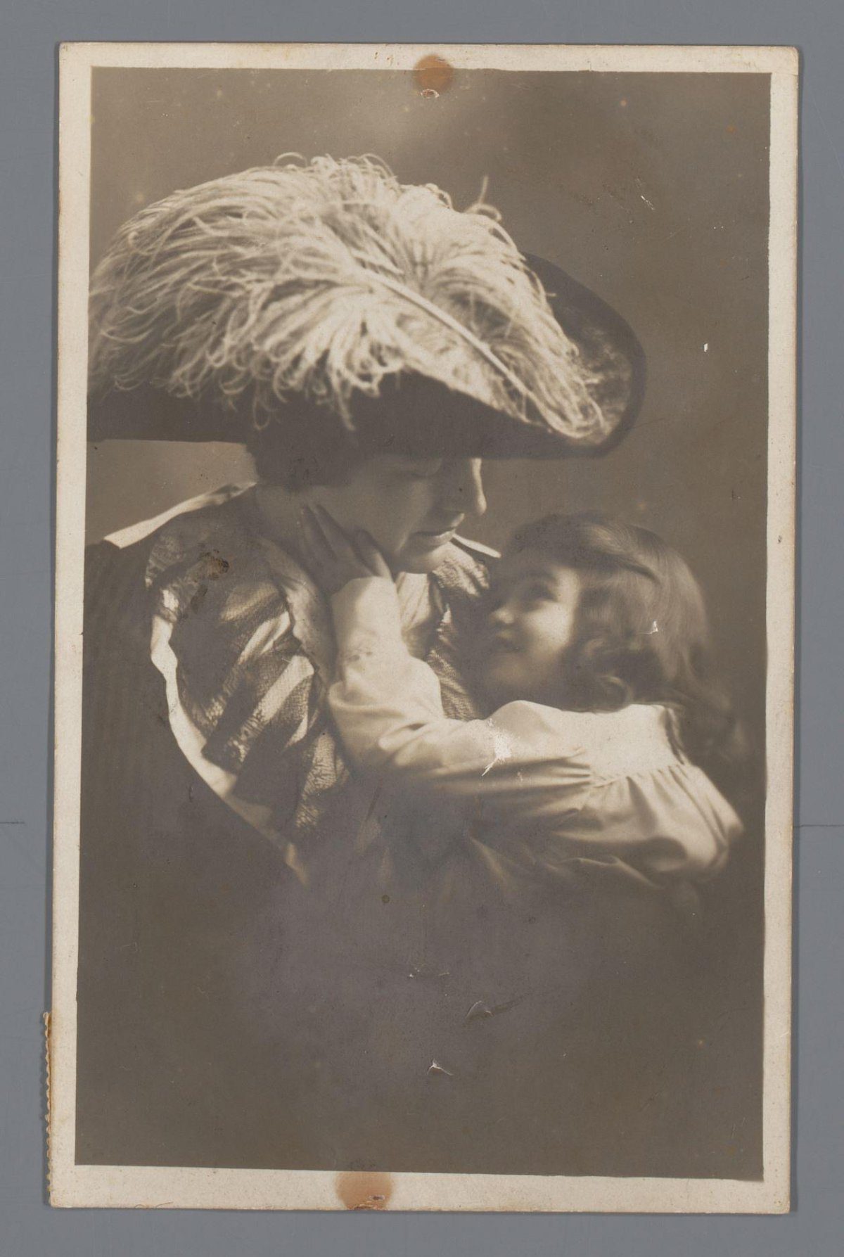 Picture postcard with photograph of a mother with hat and a child in her arms