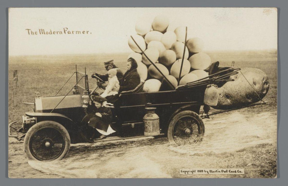 Picture postcard with car carrying four people and a pair of giant eggs and a giant potato at the rear