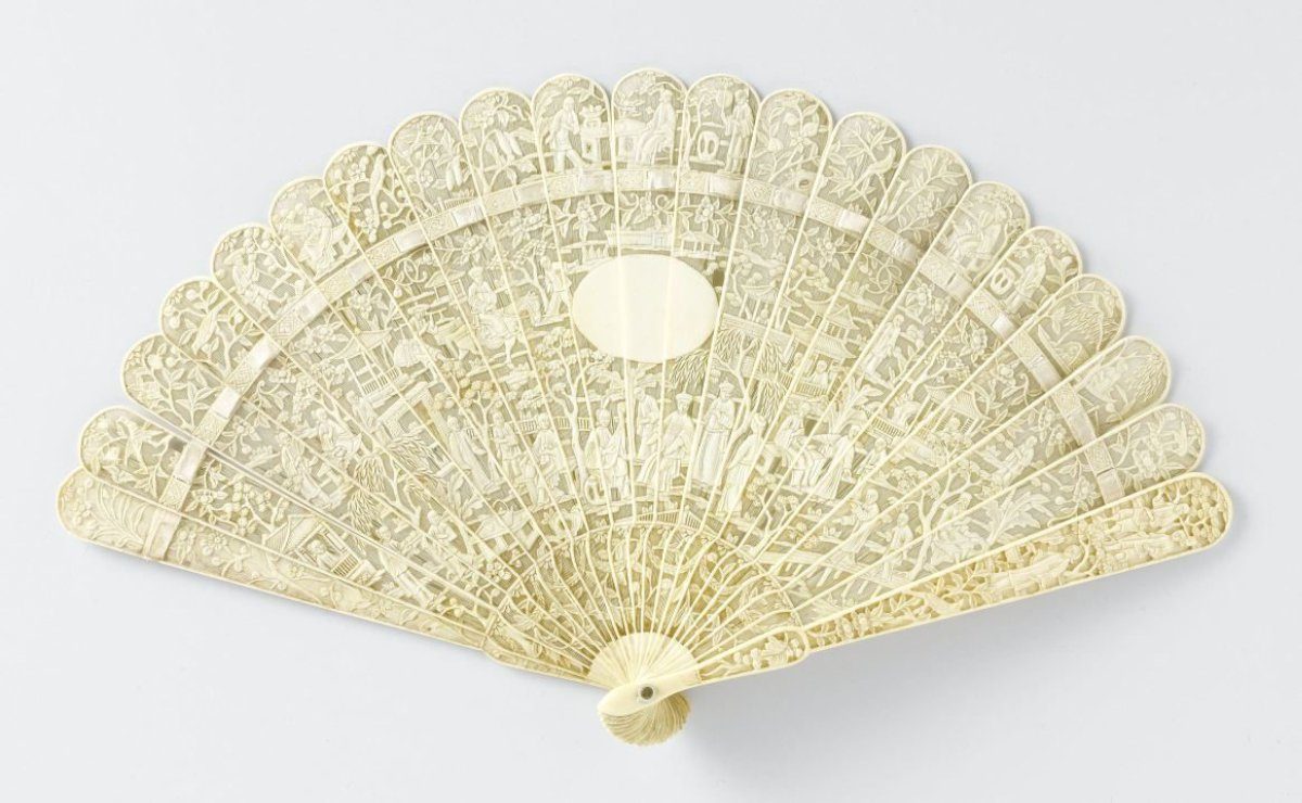 Brisé fan of openwork and relief-carved ivory featuring scenes from Chinese life with pagodas, houses, trees, and an undecorated oval medallion in the centre