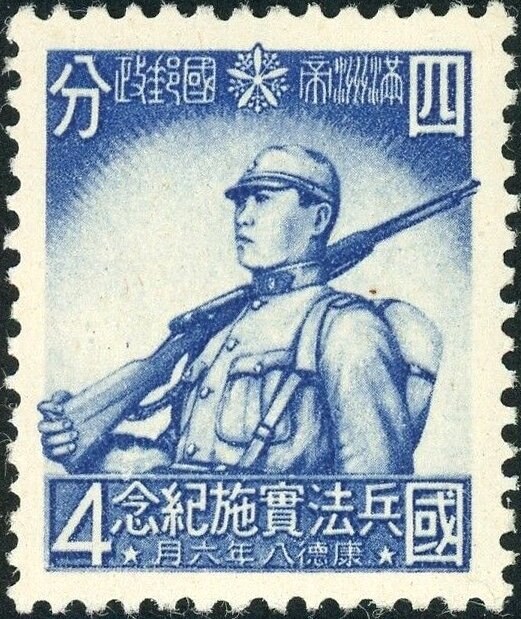 Photograph of a stamp from this issue (Wikimedia Commons file “Stamp of Manchukuo - 1941 - Colnect 365395 - Enforcement of Conscription Law.jpeg”). The paper, perforation or watermark variety shown cannot be confirmed from the photograph.