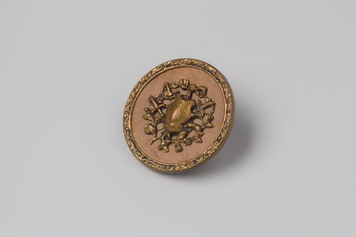 Button of copper and wood, as a fret-sawn, applied copper trophy, with a cuirass