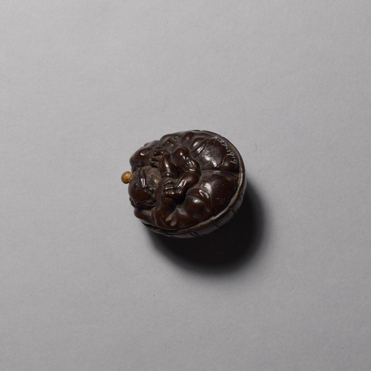 Netsuke in wood of a demon crouching beneath an old palm hat, signed Masakazu, c.1800, Japan
