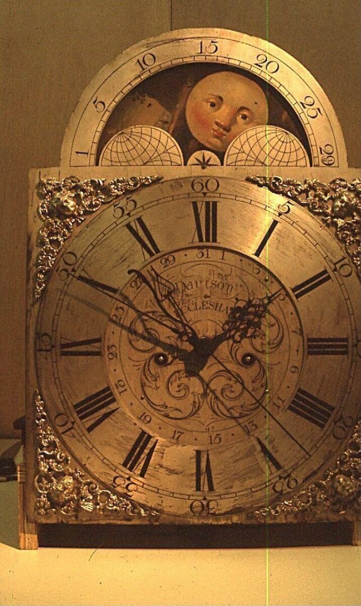 Month-going longcase clock of carved mahogany and pinewood, with gilt-brass and brass fittings, the frieze of the hood veneered and painted in colours with flowers. The silvered arched dial signed in black, 'DAVISON / ECCLESHAM', ca. 1775