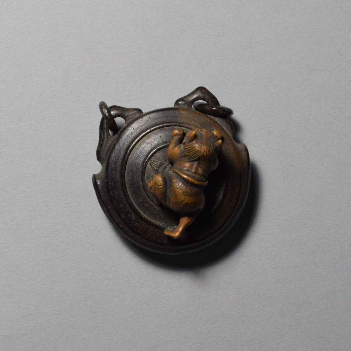 Netsuke in wood of an oni (demon) on a gong, 19th century, Japan