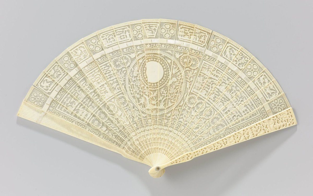 Brisé fan of ivory, scored and with openwork- and relief-carved sticks showing a Chinese landscape, mountains, pavilions, birds, and an undecorated medallion in the center